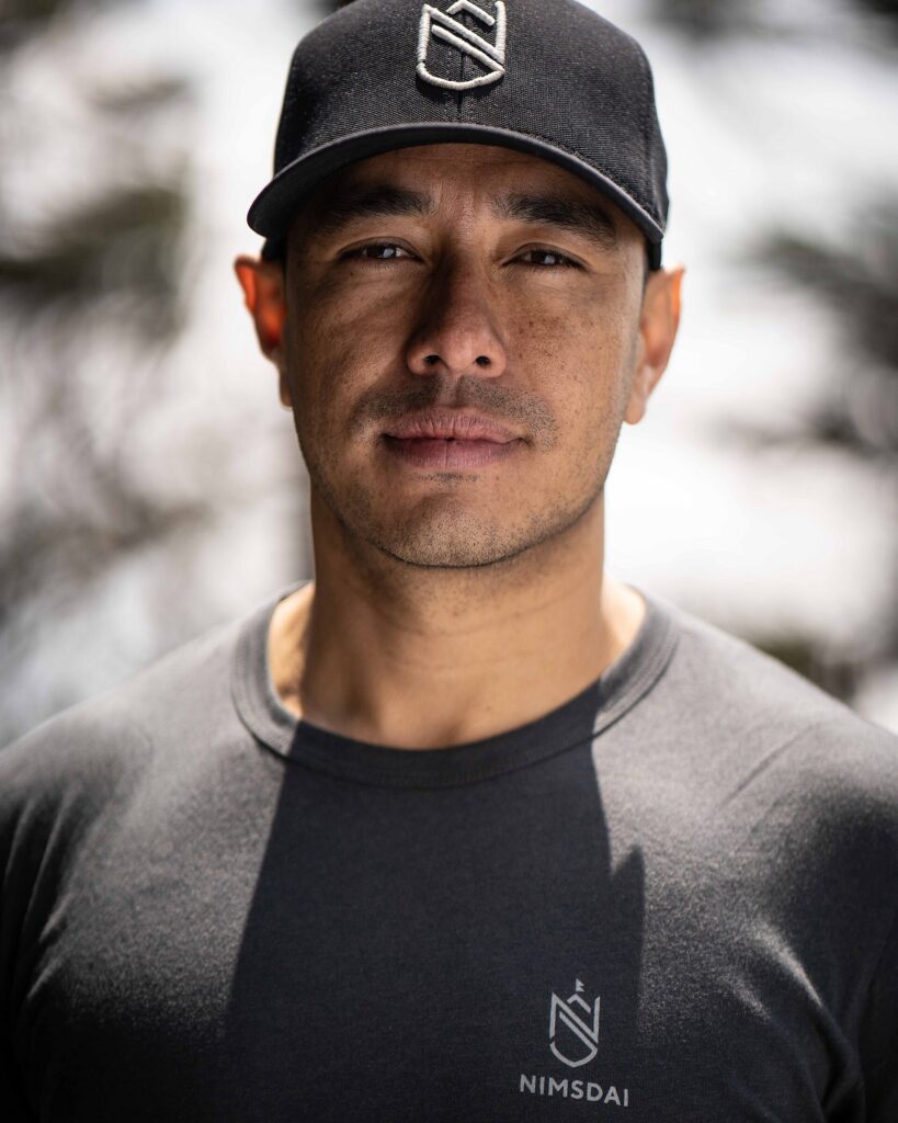 Portrait of Nirmal Purja in a black Nimsdai cap and T-shirt at Everest Base Camp, April 2021.